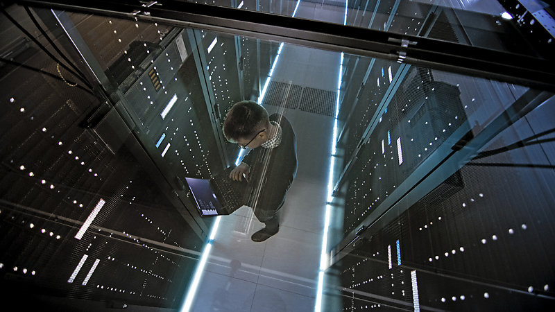Top view through glass ceiling of an IT engineer working in a server room.