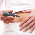 Close-up of the belly of a woman injecting herself with an insulin pen.