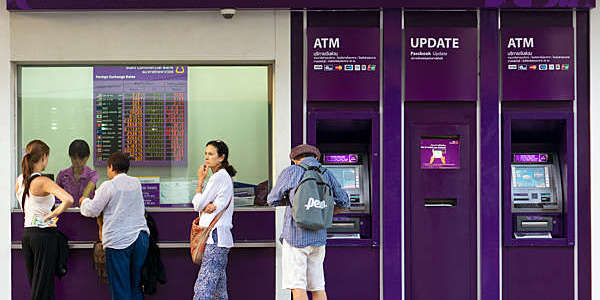 People wait to change money at a currency exchange counter.