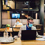 Employees wearing masks sit a safe distance apart in the office.