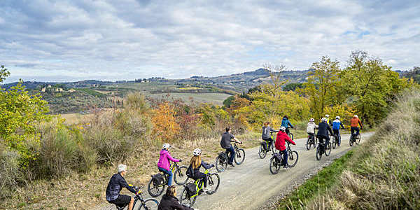 A group of cyclists on e-bikes pedal through the famous “calanchi di Certaldo” in the Italian Toscana region.