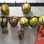 Row of yellow safety helmets hanging from a wooden rack at a mining site.