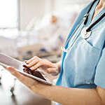 Midsection of a female medical professional using digital tablet in hospital.