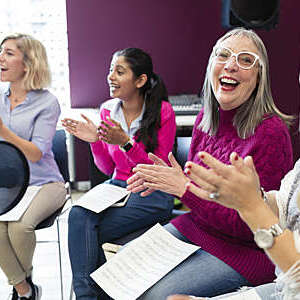 Happy womens choir with sheet music singing in music recording studio