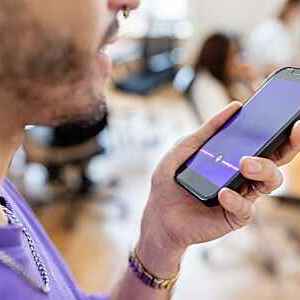 Close-up of man recording voice message on cellphone at office. Cropped shot of businessman recording a voice message on mobile phone.